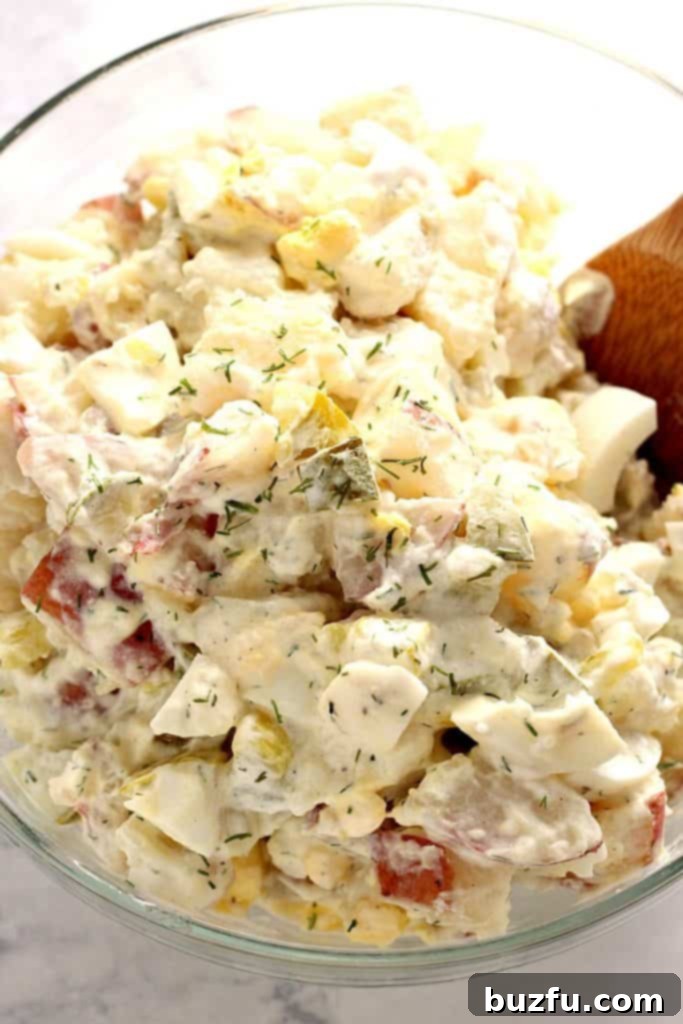 Dill pickle potato egg salad in glass mixing bowl.