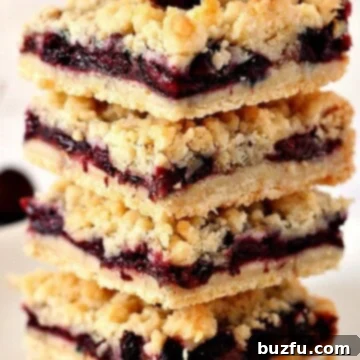 Cherry Pie Crumb Bars in a stack with fresh cherry on top.