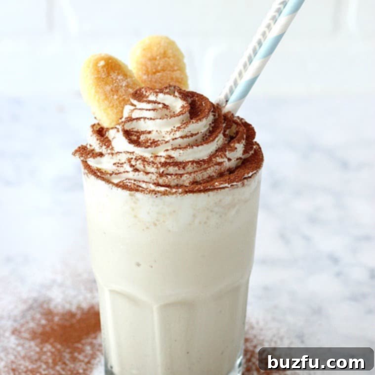 Creamy Tiramisu Milkshake Garnished with Cocoa and Ladyfingers A close-up of a delectable Tiramisu Milkshake, showcasing its smooth texture, the delicate cocoa powder on top of whipped cream, and the crunchy ladyfinger cookies standing tall, ready for a delightful treat.