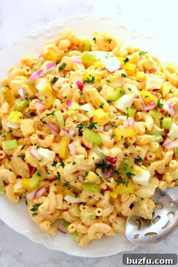 Deviled Egg Macaroni Salad on large white plate, garnished with fresh herbs.