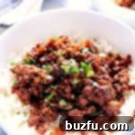 Korean Beef with rice in a white bowl, garnished with sesame seeds.