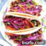 Korean beef tacos on a white plate, filled with meat and slaw.