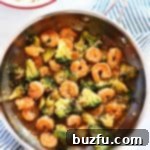 Shrimp, broccoli, and stir-fry sauce simmering in a pan.