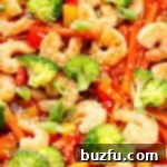 Shrimp stir fry cooking in a pan with colorful vegetables.
