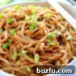 Thai Peanut Noodles in a bowl, garnished with peanuts and herbs.
