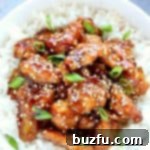 Chicken with sesame sauce on rice in a bowl, garnished with sesame seeds.