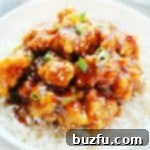 General Tso's chicken served on a bed of rice on a plate.