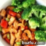 Chicken with broccoli and cashews in a white bowl, coated in sauce.
