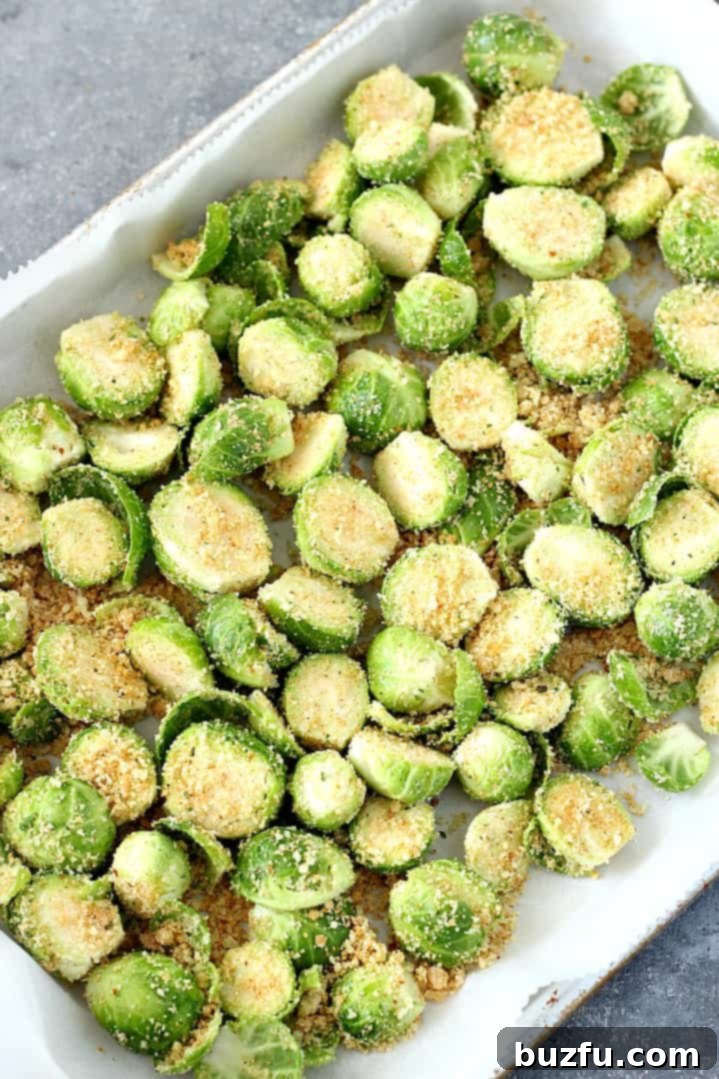 Brussels sprouts with Parmesan and breading on a baking sheet, ready for roasting.