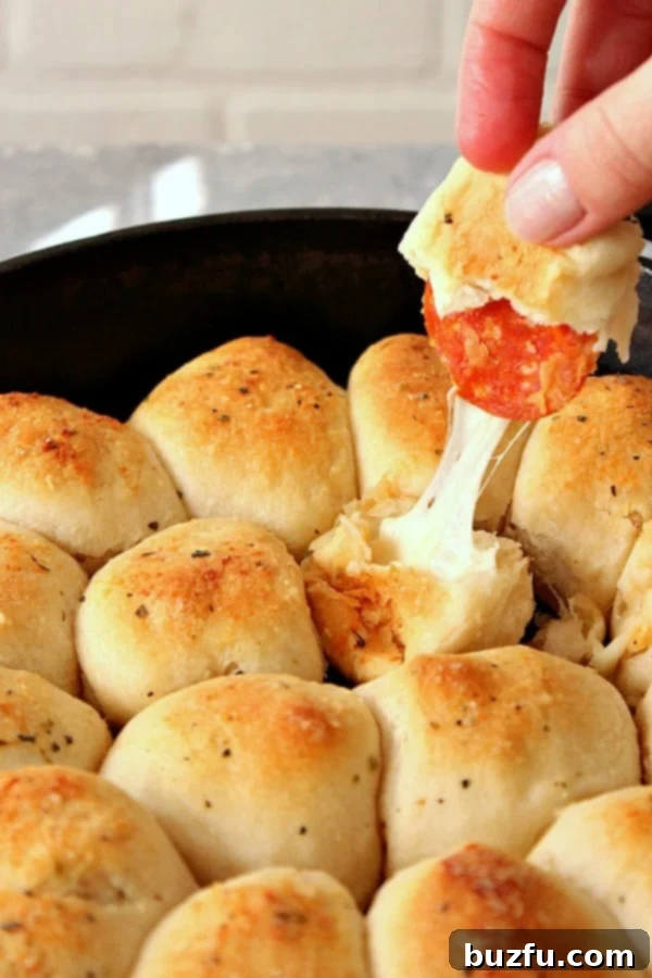 Easy Skillet Pizza Rolls: Perfect for Parties and Game Days! Pulling a golden-brown Skillet Pizza Roll from a hot cast iron skillet, showcasing its melted cheese and pepperoni filling.