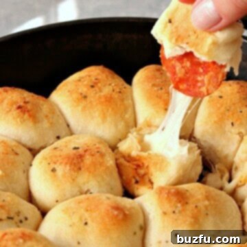 Effortless Skillet Pizza Roll Delight 2 Pulling a golden-brown Skillet Pizza Roll from a hot cast iron skillet, showcasing its melted cheese and pepperoni filling.