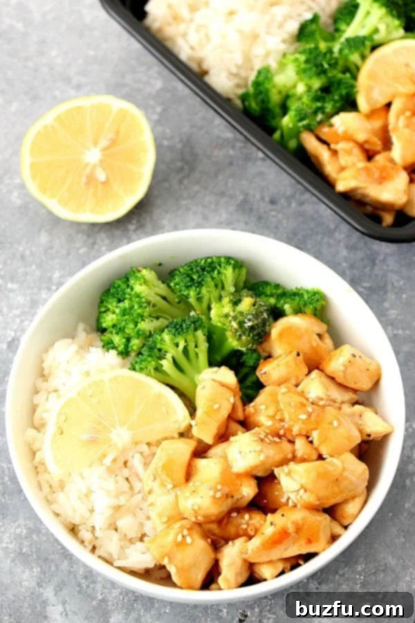 A beautifully plated Honey Lemon Chicken in a bowl, showcasing the succulent chicken pieces glazed in a golden sauce, accompanied by fluffy rice and fresh green broccoli florets. This image captures the dish's irresistible appeal.