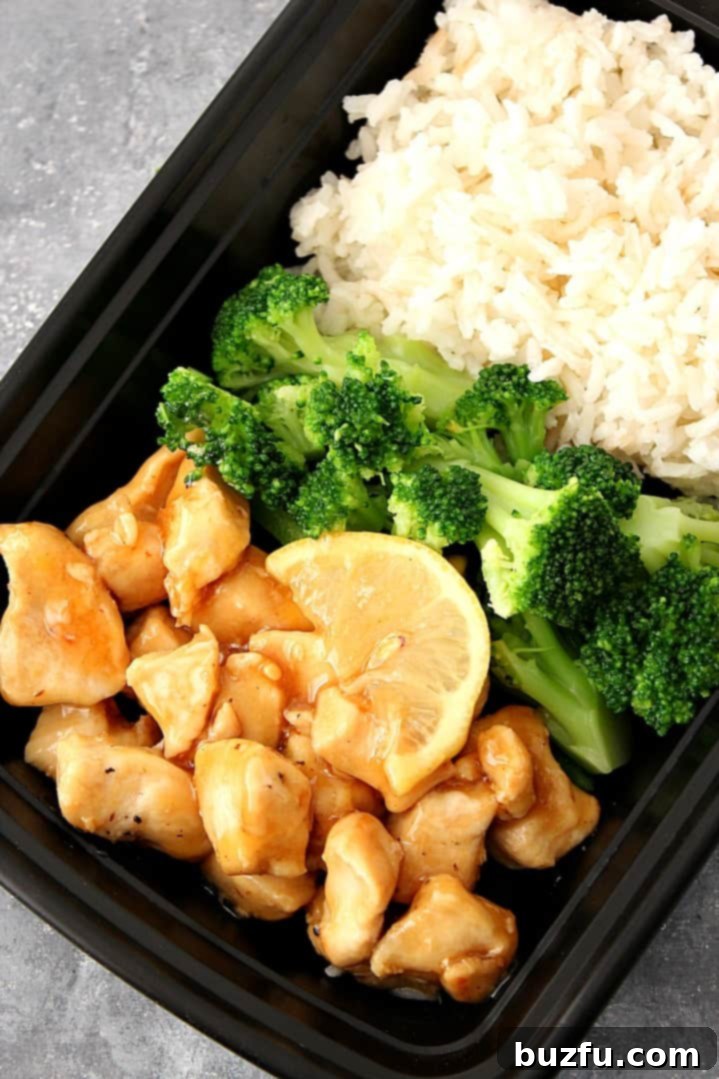 An overhead shot of a well-organized meal prep container featuring Honey Lemon Chicken, fluffy white rice, and bright green steamed broccoli, ready for a healthy and delicious meal on the go.