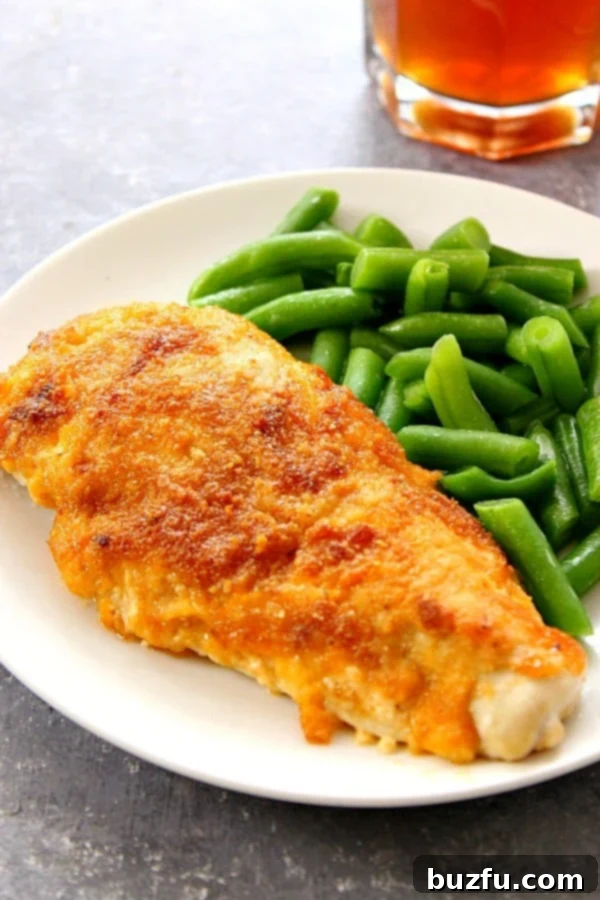 Delicious Easy BBQ Cheddar Chicken served on a white plate with a side of fresh green beans, ready to be enjoyed.
