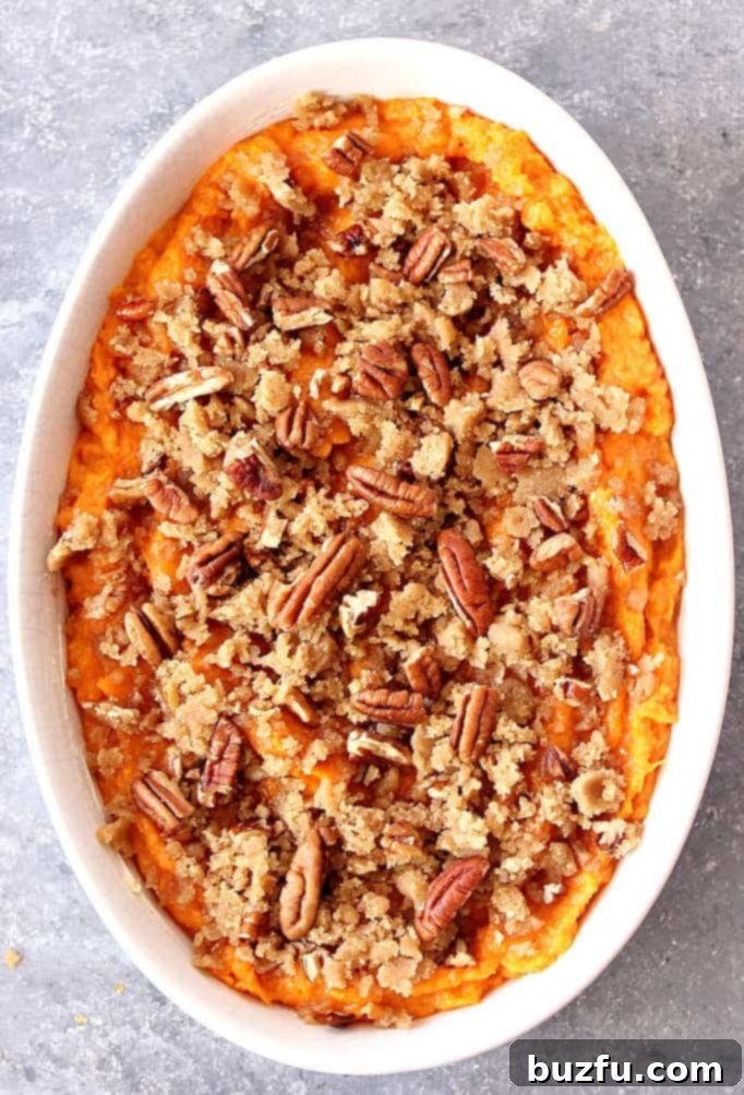 Easy Sweet Potato Casserole Recipe Overhead shot of sweet potato casserole with pecan topping in white baking dish.
