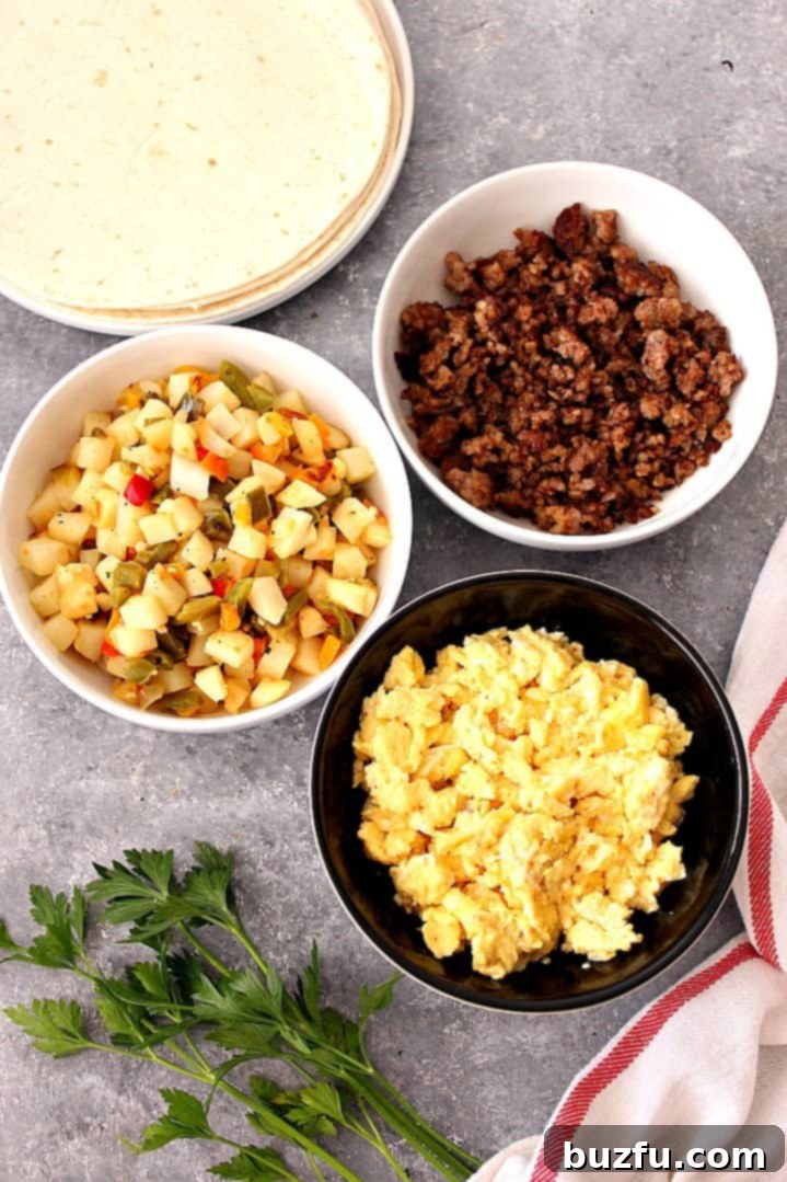 Overhead shot of potatoes in bowl, scrambled eggs in bowl and cooked sausage in bowl, next to tortillas.