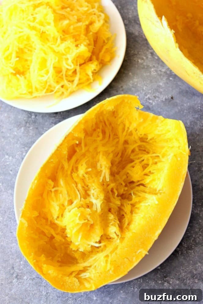 Overhead shot of Instant Pot spaghetti squash half on white plate, showcasing its golden strands ready to be served.