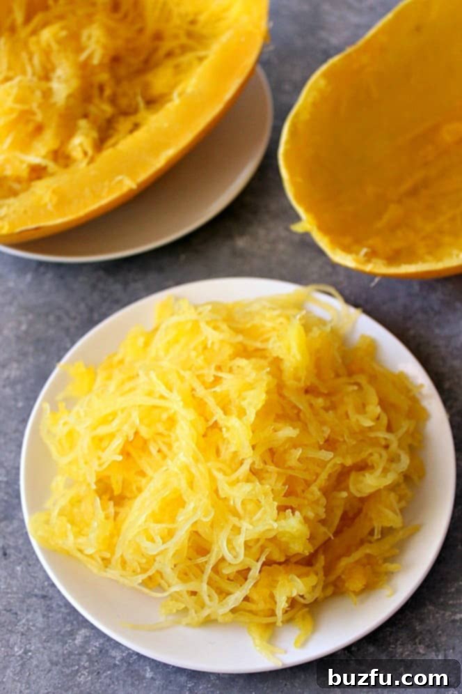 Side shot of perfectly cooked spaghetti squash on white plate, with the empty skin shell on the side, highlighting the success of the Instant Pot method.