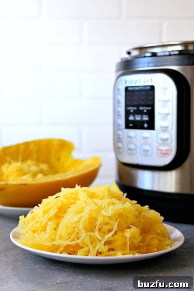 Side shot of cooked spaghetti squash on white plate, with a shining Instant Pot in the background, symbolizing efficiency and ease.