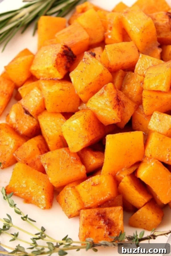 Cubed and roasted butternut squash on a plate, garnished with fresh herbs.