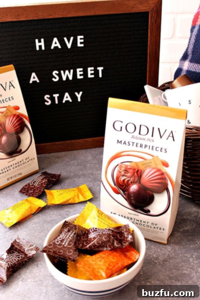 A close-up of Godiva Masterpieces chocolates and a coffee mug in a guest welcome basket.