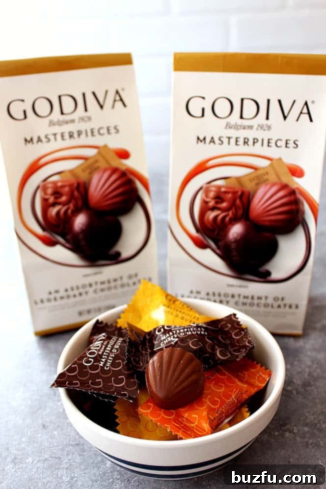A guest reaching for a Godiva Masterpiece chocolate from a welcome basket.