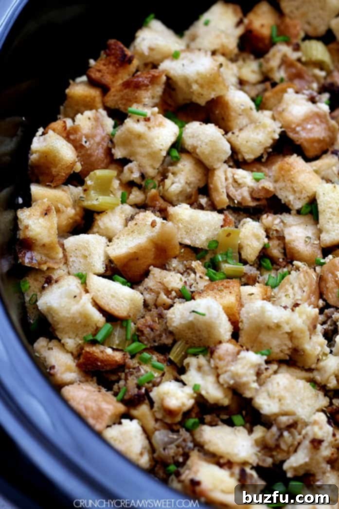 Hearty slow cooker sausage stuffing in a ceramic slow cooker, garnished with fresh herbs.