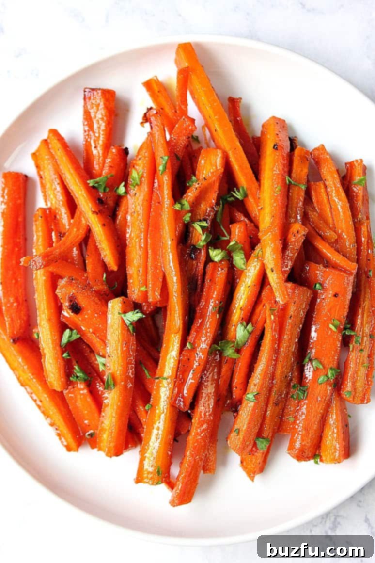 A vibrant pile of brown sugar roasted carrots, glistening and caramelized, in a white serving dish.