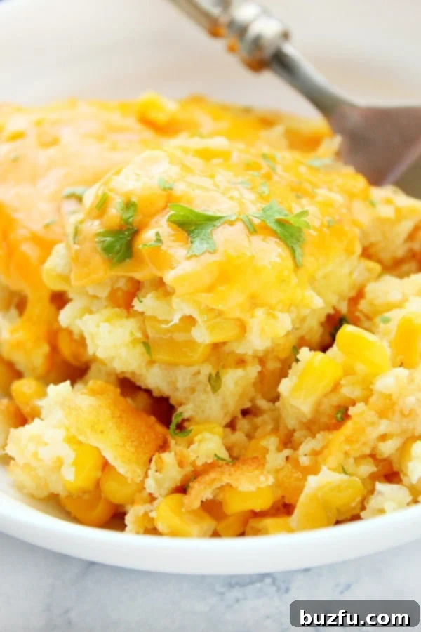 A golden-brown Sweet Corn Casserole in a serving bowl, with a fork gently scooping a portion.