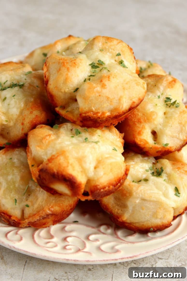 A close-up of cheesy garlic Parmesan pull-apart rolls, fresh out of the oven, sprinkled with herbs.