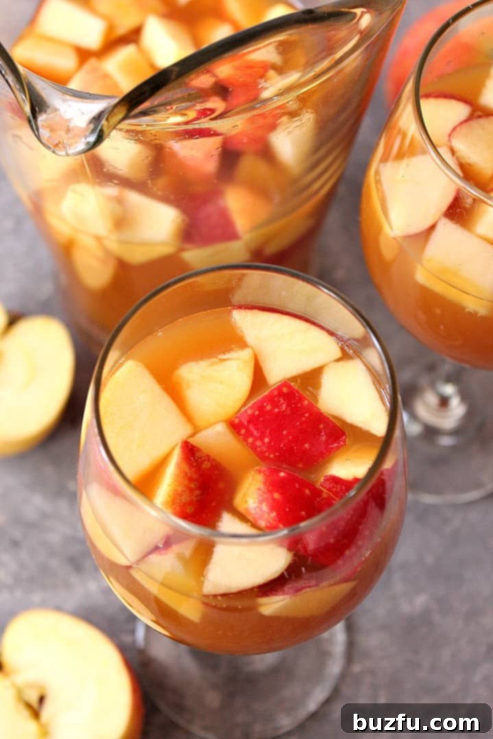 A pitcher of vibrant caramel apple sangria filled with apple slices, ready for pouring into glasses.