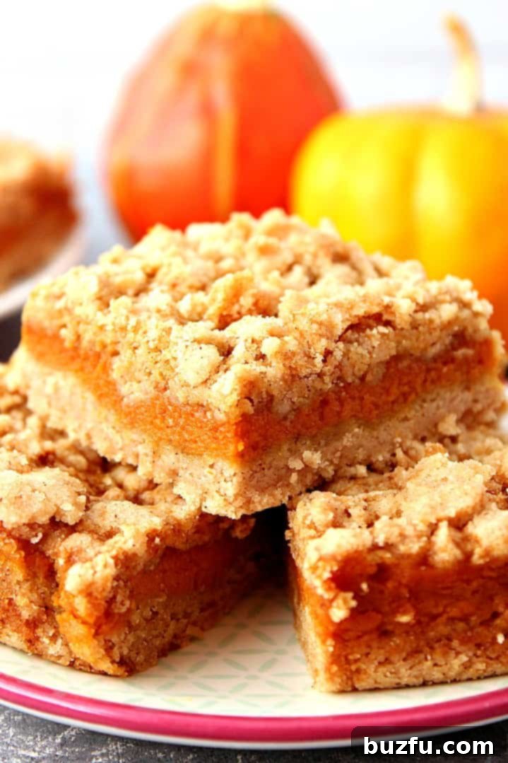 Slices of pumpkin pie bars, topped with a dollop of whipped cream and a sprinkle of cinnamon.