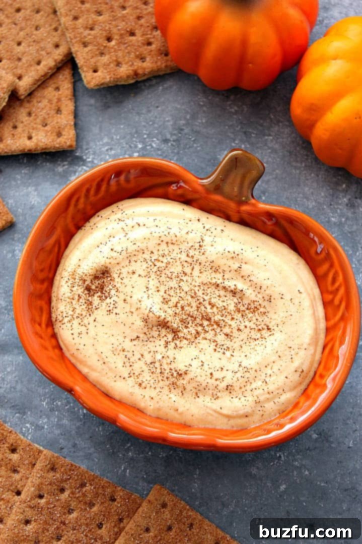 A festive bowl of creamy pumpkin cheesecake dip, garnished with a generous cinnamon crumb topping.