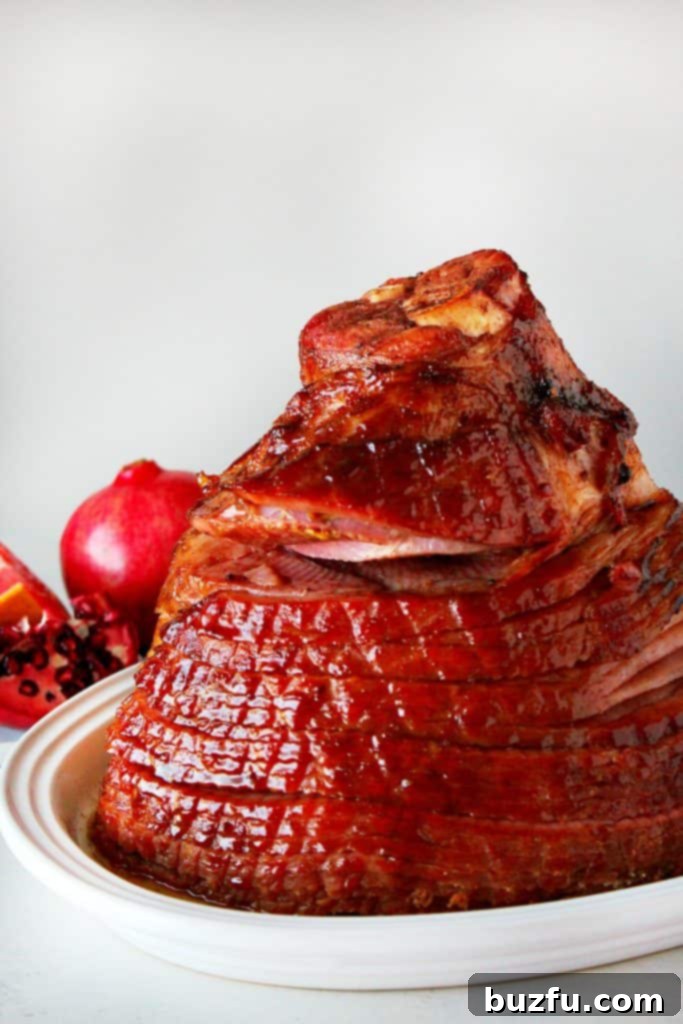 A glistening baked spiral-cut ham served elegantly on a white platter, ready for carving.