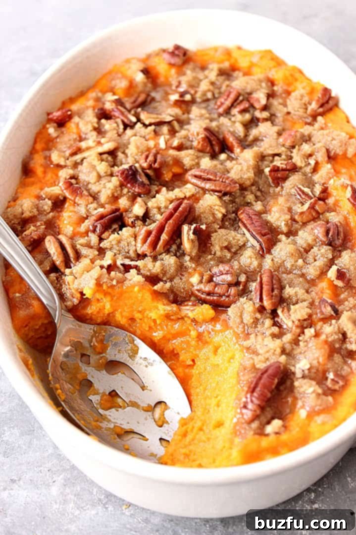 A close-up shot of a rich, golden sweet potato casserole with a glistening praline topping.