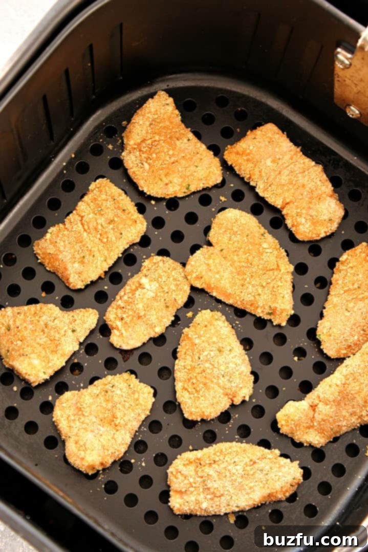Crispy Air Fried Chicken Nuggets: A Family Favorite Perfectly cooked Air Fryer Chicken Nuggets arranged neatly in an air fryer basket, showing their golden-brown, crispy exterior. A testament to a healthier, easy homemade dinner.