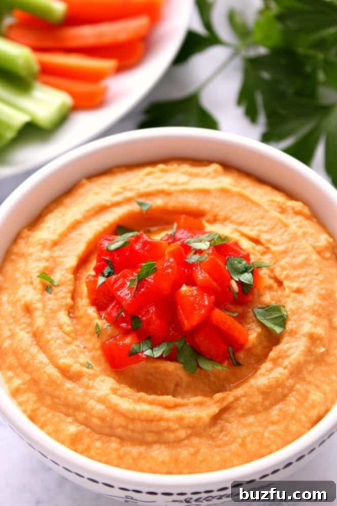 Vibrant Roasted Red Pepper Hummus served in a pristine white bowl, set against a elegant marble backdrop, garnished with fresh herbs and a drizzle of olive oil.