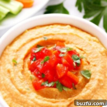 Roasted Red Pepper Hummus in a white bowl on marble board.