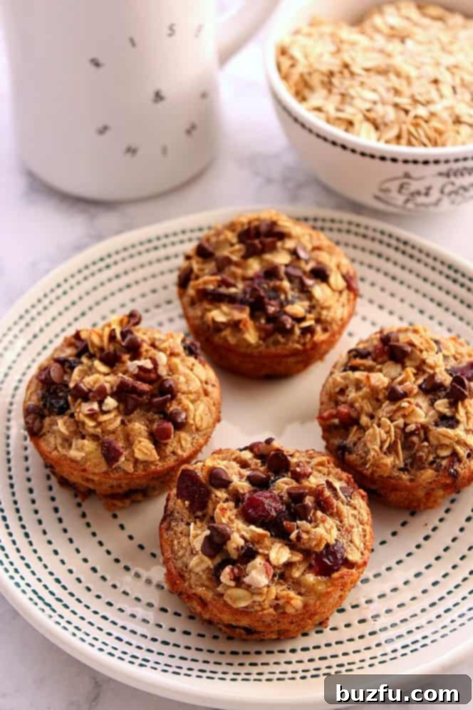 Easy Baked Oatmeal Cups Recipe - hearty and filling oatmeal baked into muffin cups. Perfect breakfast idea for busy days! Side shot of oatmeal cups on plate with blue design, white mug and a bowl with dry oats in the background.