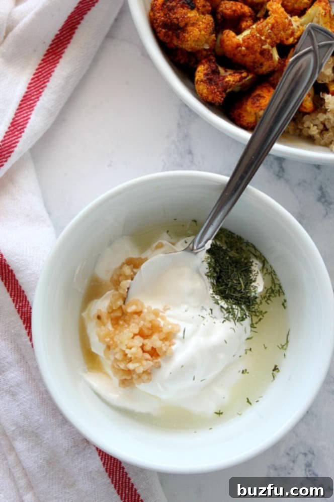 Creamy garlic dill sauce in a small white bowl, garnished with fresh dill, ready to be served with Shawarma Roasted Cauliflower.
