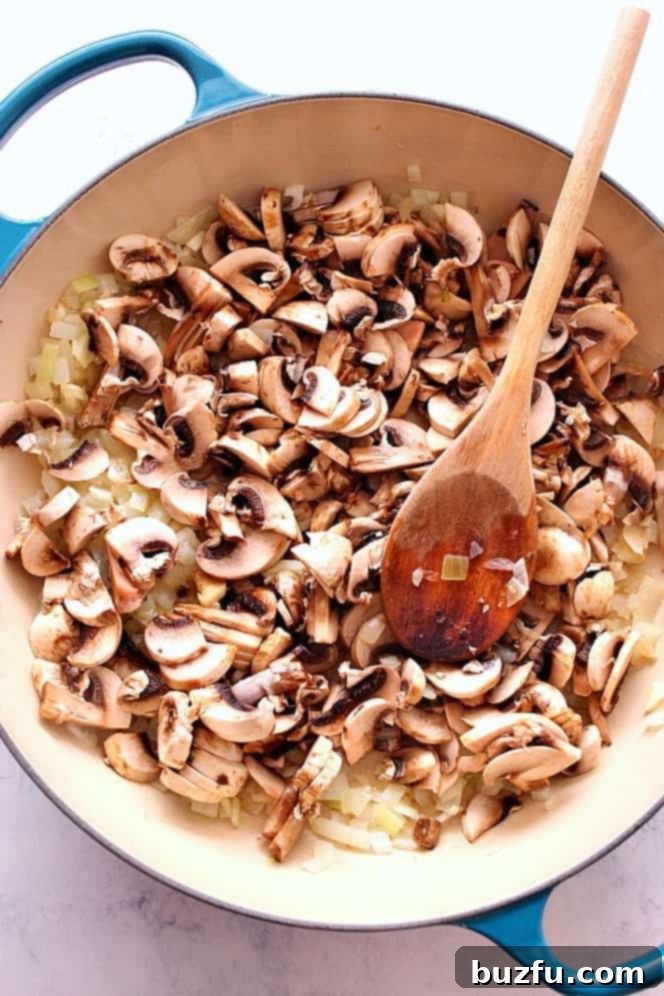 Mushrooms and onions cooking in a skillet for a flavorful stroganoff base.