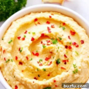 Velvety No-Tahini Hummus 3 Easy Hummus without tahini in a dip bowl, garnished with herbs and a drizzle of olive oil.