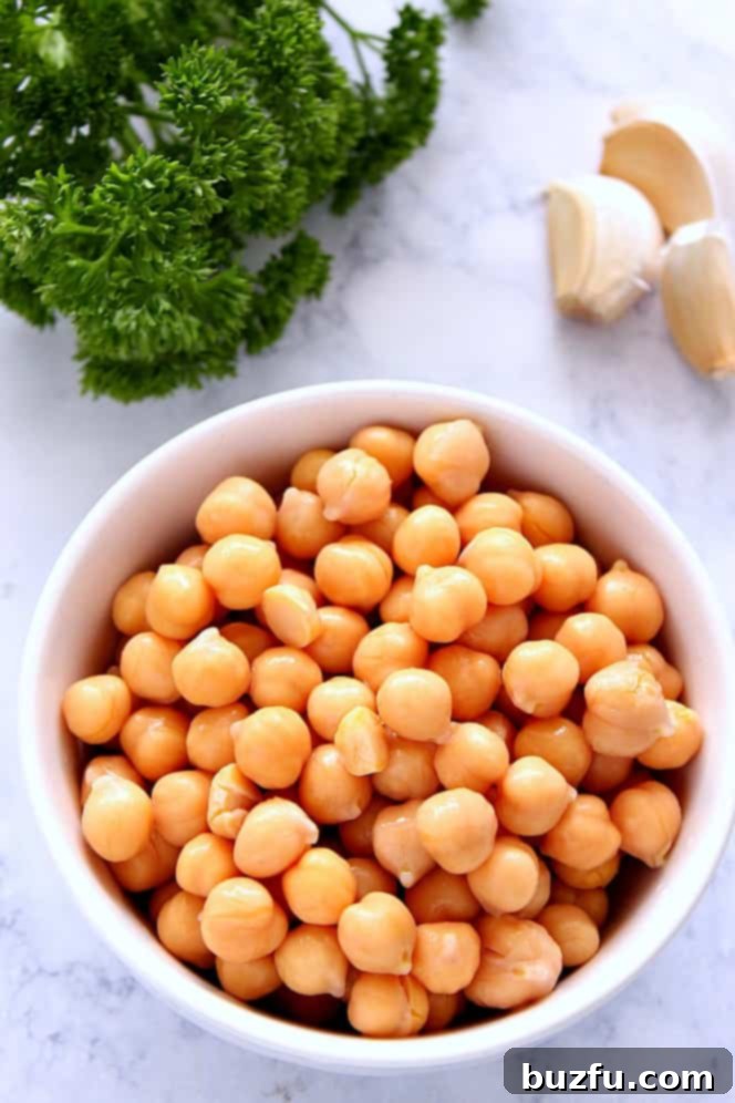 Easy Hummus without Tahini - simple recipe for hummus made with just a few ingredients and no tahini. So much better than store-bought stuff. Close-up of a bowl filled with plump, cooked garbanzo beans (chickpeas), the main ingredient for delicious homemade hummus.