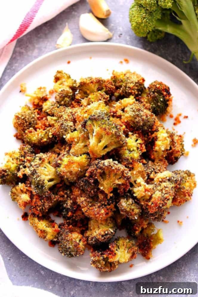 A serving of perfectly roasted garlic parmesan broccoli on a white plate, ready to be enjoyed.