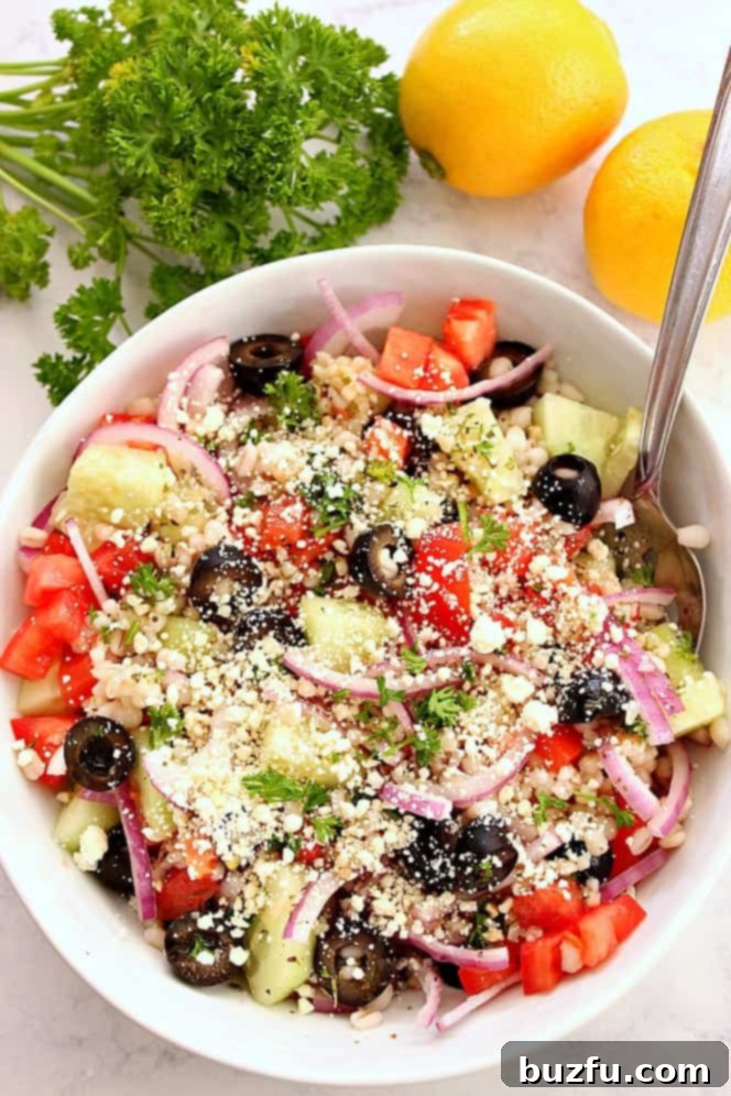 Vibrant Greek salad in a bowl, garnished with fresh lemon wedges and parsley, ready for serving.