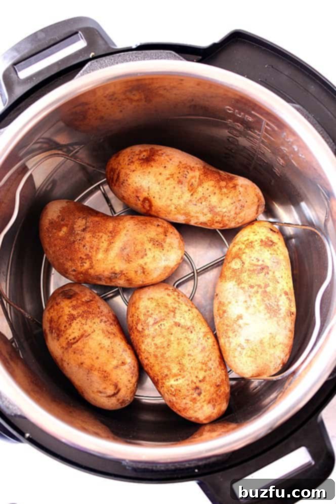 Perfect Instant Pot Baked Potatoes 3 Close-up of fluffy baked potatoes cooking inside an Instant Pot, showing the steam and trivet setup.