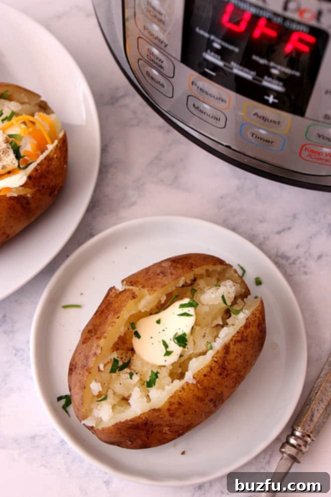 Perfect Instant Pot Baked Potatoes 4 A perfectly cooked baked potato, split open and generously topped with butter, chives, and sour cream, on a white plate after being cooked in an Instant Pot.