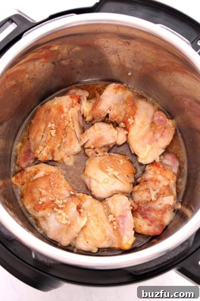 Close-up view of boneless, skinless chicken thighs browning in the Instant Pot insert.