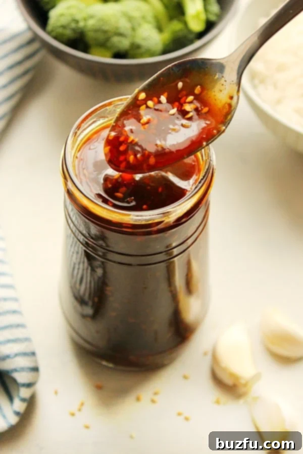 Homemade Teriyaki Sauce recipe - the best and easiest sauce for Asian dishes! You only need a few ingredients to make it. Homemade teriyaki sauce on a spoon over a jar, with sesame seeds visible.