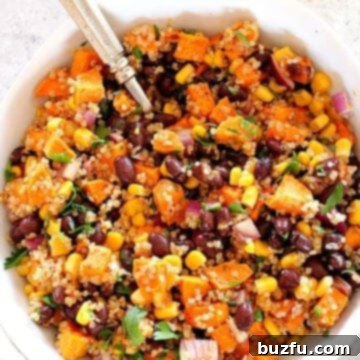 Sweet potato quinoa salad in a white bowl with a fork, on a gray board.